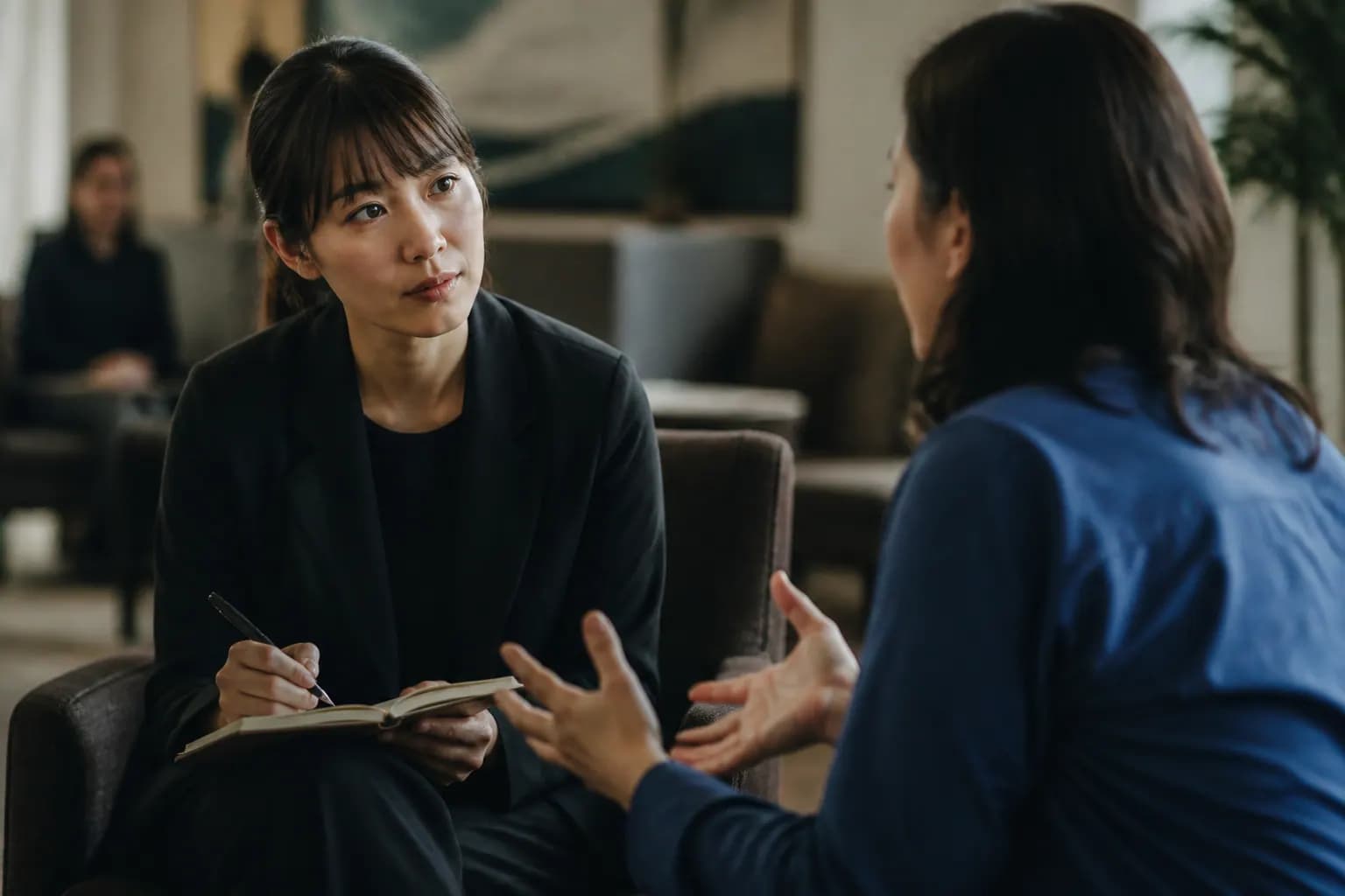 Researcher conducting a one-to-one customer interview with a notebook and recorder.